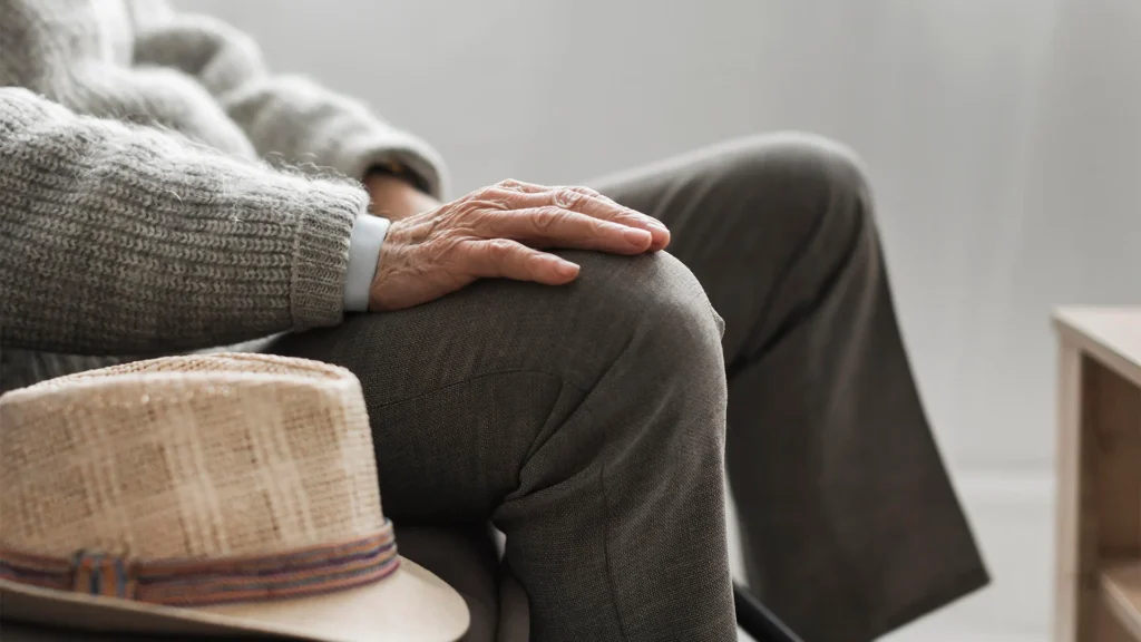 Side View Of An Old Man With His Hand On Knee